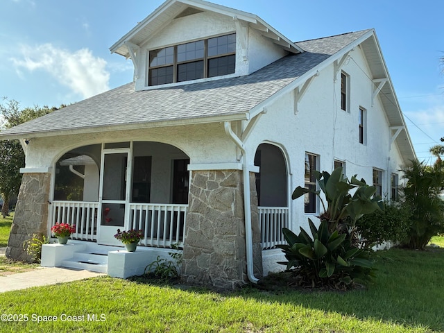 415 2nd Ave, Indialantic, FL 32903 - view of front of house with roof with shingles, covered porch, stone siding, stucco siding, and a front yard