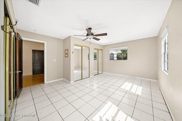 415 2nd Ave, Indialantic, FL 32903 - unfurnished bedroom featuring a textured ceiling, two closets, light tile patterned floors, and a ceiling fan