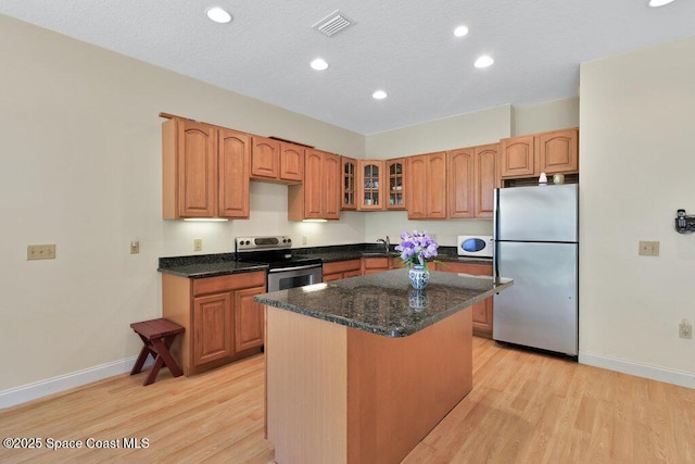 3825 Allen Ave, Micco, FL 32976 - kitchen with stainless steel appliances, light wood-style flooring, recessed lighting, a kitchen island, and glass insert cabinets