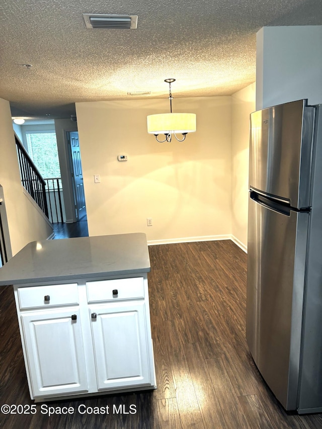 1070 Bella Vista Blvd Unit 110, Saint Augustine, FL 32084 - kitchen with freestanding refrigerator, white cabinetry, a textured ceiling, dark wood-style flooring, and dark countertops