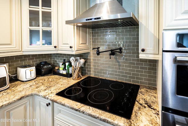 1249 Coosa Ave NE, Palm Bay, FL 32907 - kitchen with wall chimney exhaust hood, black electric stovetop, stainless steel oven, and tasteful backsplash