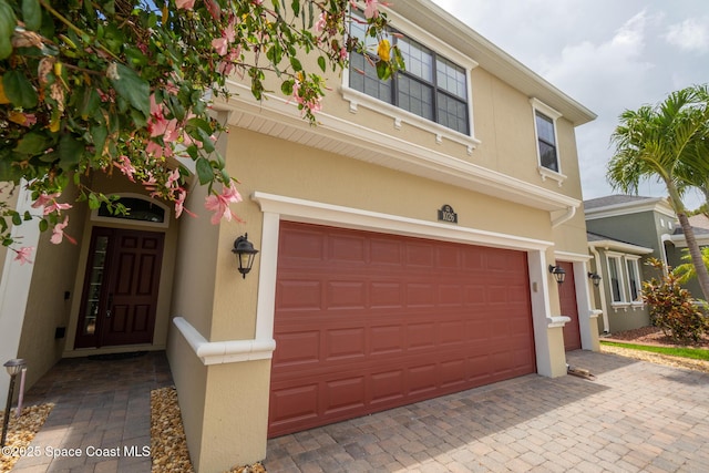 1026 Shiloh Dr, Melbourne, FL 32940 - view of front of home featuring an attached garage, stucco siding, and decorative driveway