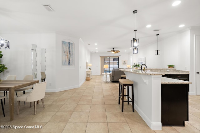 1026 Shiloh Dr, Melbourne, FL 32940 - kitchen featuring recessed lighting, light tile patterned floors, ornamental molding, light stone countertops, and a breakfast bar area