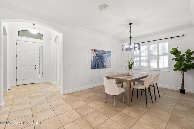 1026 Shiloh Dr, Melbourne, FL 32940 - dining space with arched walkways, light tile patterned floors, crown molding, and a chandelier