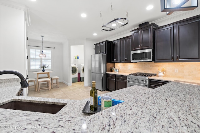 1026 Shiloh Dr, Melbourne, FL 32940 - kitchen with stainless steel appliances, washing machine and clothes dryer, light tile patterned floors, tasteful backsplash, and light stone counters