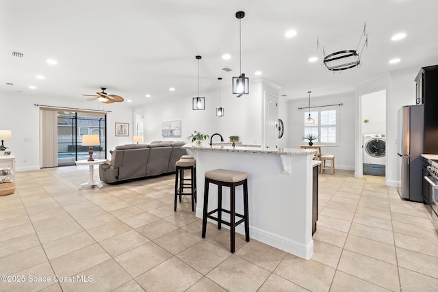 1026 Shiloh Dr, Melbourne, FL 32940 - kitchen with washer / dryer, a breakfast bar area, light tile patterned flooring, ceiling fan, and recessed lighting