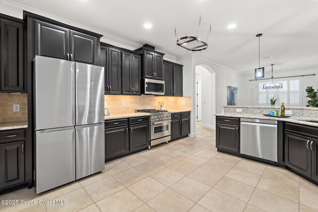 1026 Shiloh Dr, Melbourne, FL 32940 - kitchen with appliances with stainless steel finishes, dark cabinets, arched walkways, backsplash, and ornamental molding