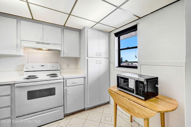 520 Palm Springs Blvd Unit 405, Indian Harbour Beach, FL 32937 - kitchen featuring electric stove, under cabinet range hood, black microwave, light countertops, and tile walls