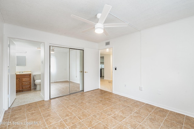 128 San Paulo Cir Unit 128, West Melbourne, FL 32904 - unfurnished bedroom with ensuite bathroom, a closet, light tile patterned floors, a ceiling fan, and a textured ceiling