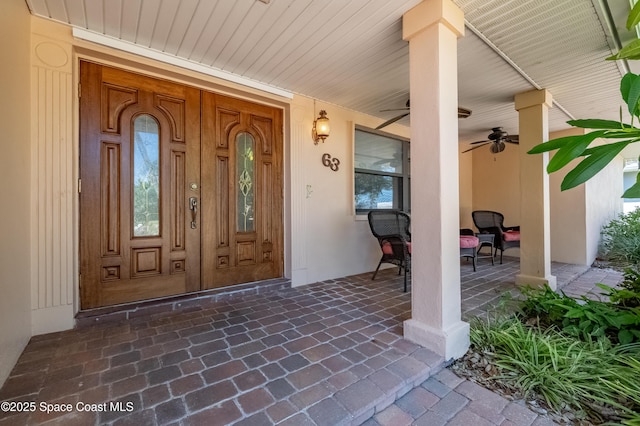 63 Yacht Haven Dr, Cocoa Beach, FL 32931 - view of exterior entry with stucco siding, a ceiling fan, and covered porch