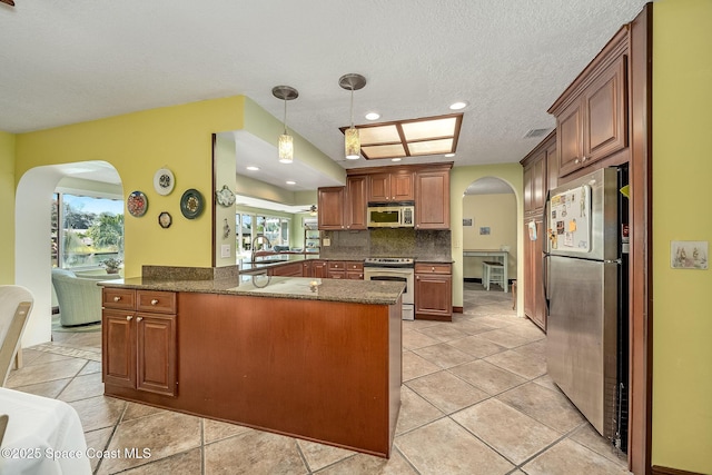 63 Yacht Haven Dr, Cocoa Beach, FL 32931 - kitchen featuring appliances with stainless steel finishes, arched walkways, a peninsula, backsplash, and light tile patterned flooring