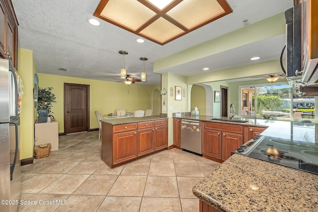 63 Yacht Haven Dr, Cocoa Beach, FL 32931 - kitchen featuring appliances with stainless steel finishes, ceiling fan, a peninsula, arched walkways, and brown cabinets
