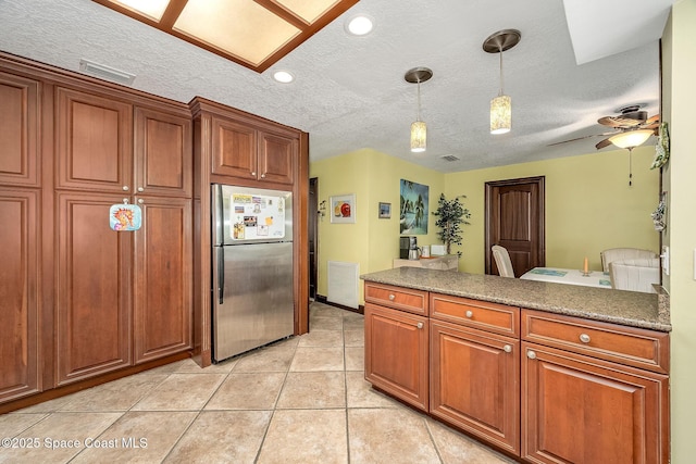 63 Yacht Haven Dr, Cocoa Beach, FL 32931 - kitchen featuring freestanding refrigerator, decorative light fixtures, a textured ceiling, brown cabinetry, and light tile patterned flooring