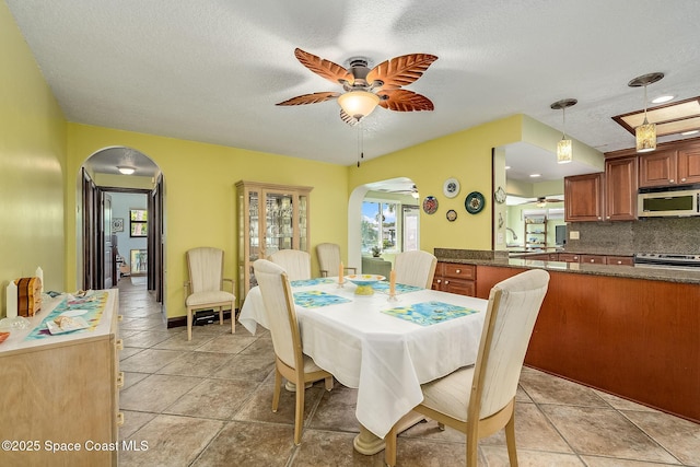 63 Yacht Haven Dr, Cocoa Beach, FL 32931 - dining space with arched walkways, ceiling fan, a textured ceiling, and light tile patterned floors