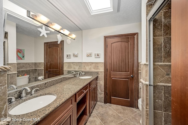 63 Yacht Haven Dr, Cocoa Beach, FL 32931 - full bathroom featuring tile walls, tile patterned floors, double vanity, wainscoting, and a textured ceiling