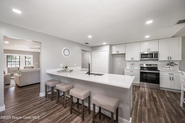 127 Friar Ct, Sebastian, FL 32958 - kitchen featuring appliances with stainless steel finishes, dark wood-style flooring, a kitchen bar, white cabinets, and recessed lighting