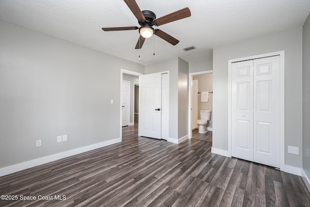 127 Friar Ct, Sebastian, FL 32958 - unfurnished bedroom featuring dark wood-style floors, multiple closets, ensuite bath, and ceiling fan