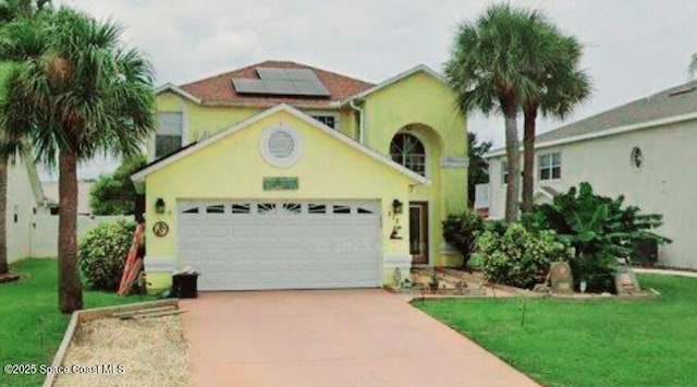 273 Provincial Dr, Indialantic, FL 32903 - mediterranean / spanish-style house with concrete driveway, roof mounted solar panels, an attached garage, a front lawn, and stucco siding
