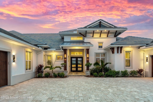 3778 Lake Adelaide Pl, Rockledge, FL 32955 - exterior entry at dusk with french doors, stucco siding, a standing seam roof, and a metal roof