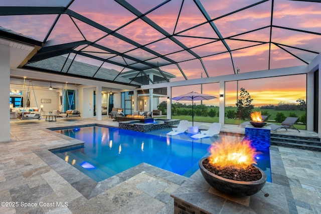 3778 Lake Adelaide Pl, Rockledge, FL 32955 - pool at dusk featuring an outdoor living space with a fire pit, a patio area, a pool with connected hot tub, and glass enclosure