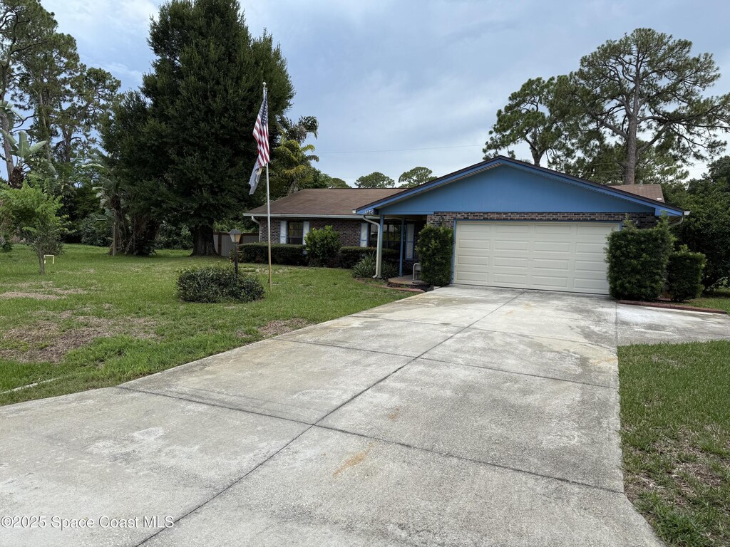 3145 1st Ln, Vero Beach, FL 32968 - ranch-style house with concrete driveway, a garage, and a front yard