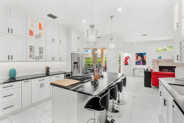 227 Loggerhead Dr, Melbourne Beach, FL 32951 - kitchen with light marble finish flooring, recessed lighting, a kitchen bar, white cabinets, and a center island