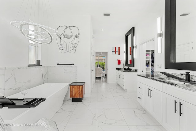 227 Loggerhead Dr, Melbourne Beach, FL 32951 - ensuite bathroom featuring two vanities, marble look tiles, a freestanding tub, a chandelier, and recessed lighting