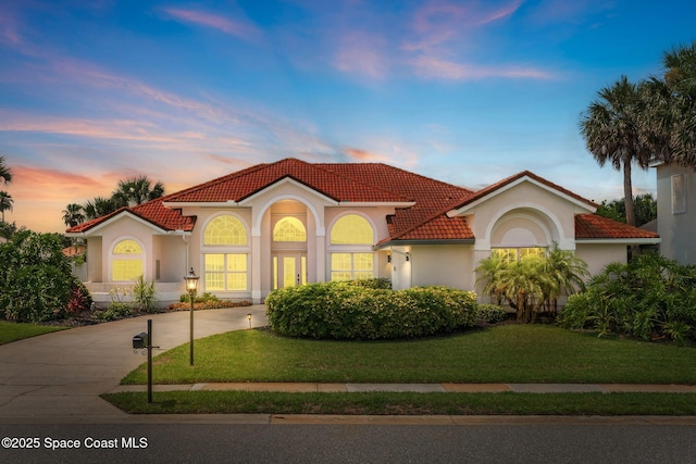 227 Loggerhead Dr, Melbourne Beach, FL 32951 - mediterranean / spanish-style house featuring stucco siding, a tiled roof, a front lawn, and driveway