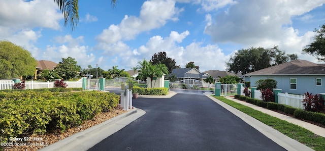 688 Naples Ct, West Melbourne, FL 32904 - view of asphalt road with a gate, a residential view, curbs, and a gated entry