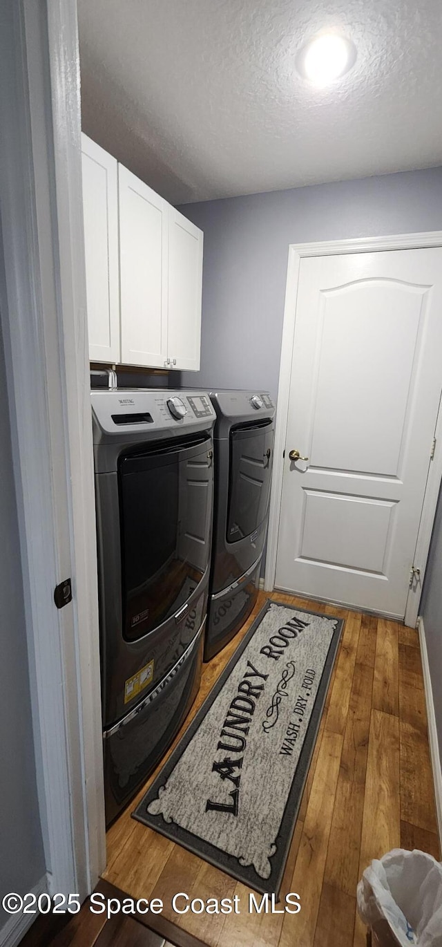 688 Naples Ct, West Melbourne, FL 32904 - laundry area with cabinet space, washer and clothes dryer, hardwood / wood-style floors, and a textured ceiling
