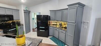 688 Naples Ct, West Melbourne, FL 32904 - kitchen featuring black refrigerator with ice dispenser, gray cabinets, light tile patterned floors, tasteful backsplash, and range with electric stovetop
