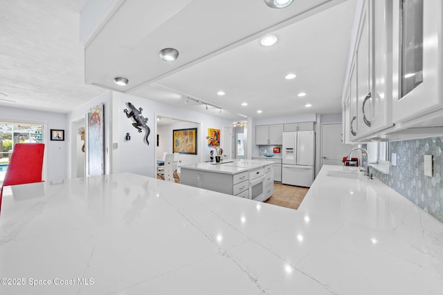 1732 Bay Shore Dr, Cocoa Beach, FL 32931 - kitchen with white refrigerator with ice dispenser, light stone counters, a center island, recessed lighting, and tasteful backsplash