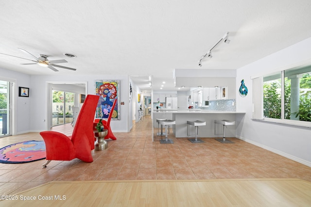 1732 Bay Shore Dr, Cocoa Beach, FL 32931 - living area featuring light tile patterned flooring, rail lighting, and a ceiling fan