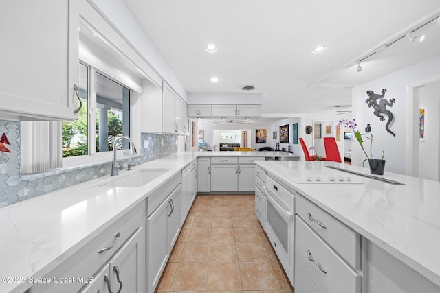 1732 Bay Shore Dr, Cocoa Beach, FL 32931 - kitchen with light stone counters, decorative backsplash, white cabinets, recessed lighting, and light tile patterned flooring