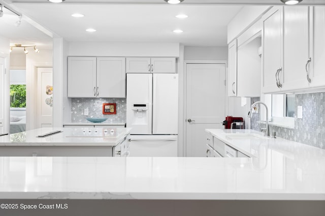 1732 Bay Shore Dr, Cocoa Beach, FL 32931 - kitchen with white fridge with ice dispenser, decorative backsplash, recessed lighting, white cabinetry, and light stone counters