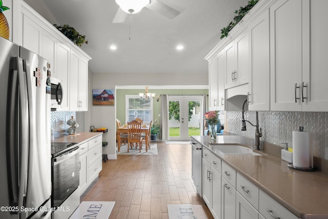 212 Olivick Cir NE, Palm Bay, FL 32907 - kitchen featuring stainless steel appliances, tasteful backsplash, a chandelier, light wood-style flooring, and white cabinets