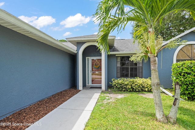 212 Olivick Cir NE, Palm Bay, FL 32907 - property entrance with stucco siding, a lawn, and roof with shingles
