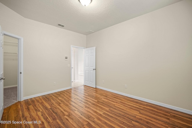 2690 Cypress Tree Trl, Saint Cloud, FL 34772 - unfurnished bedroom with wood finished floors, a walk in closet, and a textured ceiling