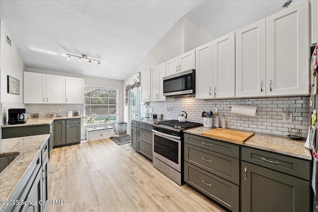 3635 Manassas Ave, Melbourne, FL 32934 - kitchen featuring stainless steel appliances, light wood-style flooring, backsplash, light stone counters, and white cabinetry