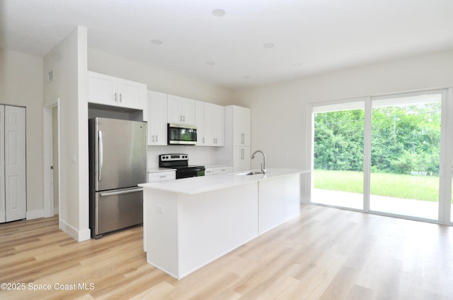 1043 Walden Blvd SE, Palm Bay, FL 32909 - kitchen with appliances with stainless steel finishes, light wood-type flooring, white cabinetry, light countertops, and a kitchen island with sink