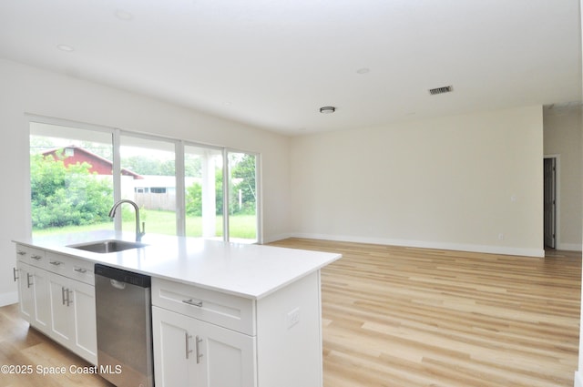 1043 Walden Blvd SE, Palm Bay, FL 32909 - kitchen featuring stainless steel dishwasher, open floor plan, light wood finished floors, a kitchen island with sink, and white cabinetry