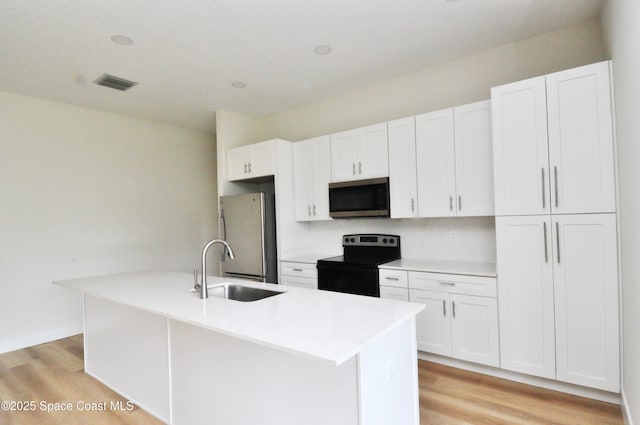 1043 Walden Blvd SE, Palm Bay, FL 32909 - kitchen with appliances with stainless steel finishes, light wood-type flooring, a center island with sink, and white cabinets