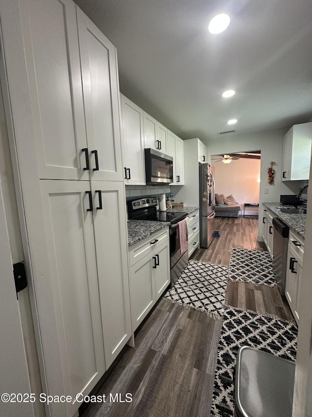 6240 Grissom Pkwy, Cocoa, FL 32927 - kitchen with appliances with stainless steel finishes, white cabinets, dark wood-type flooring, light stone countertops, and ceiling fan