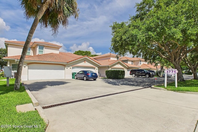 1720 Minutemen Cswy Unit 3, Cocoa Beach, FL 32931 - view of front facade with driveway, stucco siding, an attached garage, a tiled roof, and a front lawn