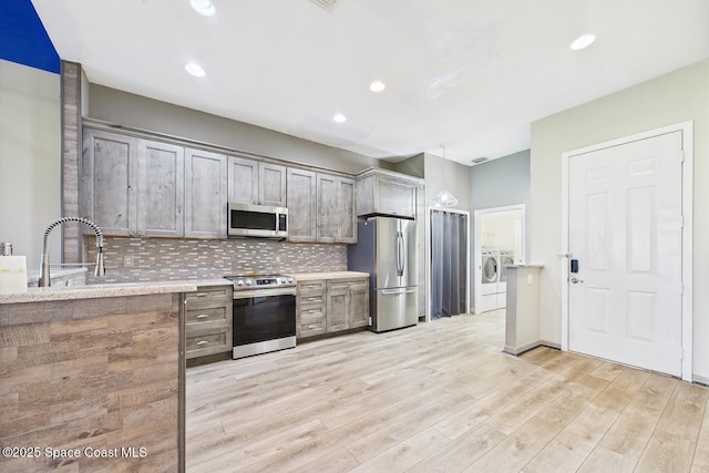 1720 Minutemen Cswy Unit 3, Cocoa Beach, FL 32931 - kitchen with appliances with stainless steel finishes, independent washer and dryer, tasteful backsplash, light countertops, and light wood-type flooring