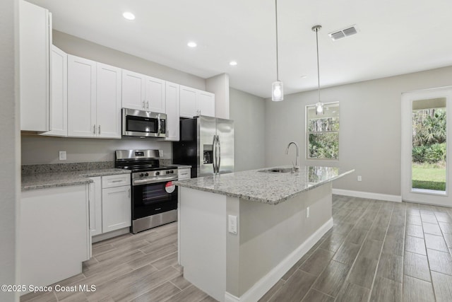 1049 Towhlen St SE, Palm Bay, FL 32909 - kitchen with stainless steel appliances, wood tiled floors, healthy amount of natural light, recessed lighting, and white cabinets
