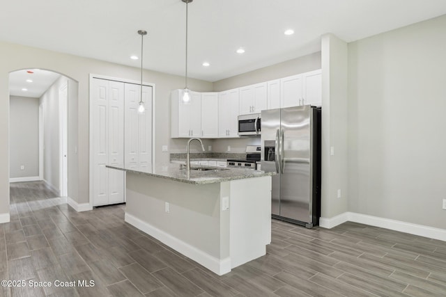 1049 Towhlen St SE, Palm Bay, FL 32909 - kitchen featuring appliances with stainless steel finishes, wood tiled floors, arched walkways, recessed lighting, and white cabinets