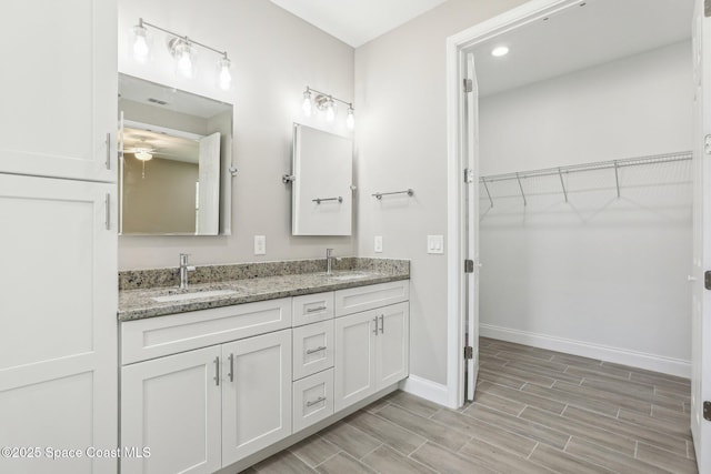 1049 Towhlen St SE, Palm Bay, FL 32909 - bathroom featuring double vanity, wood finished floors, a walk in closet, and ceiling fan