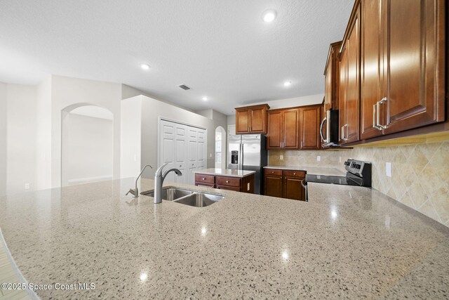 3645 Salt Marsh Cir, West Melbourne, FL 32904 - kitchen with stainless steel appliances, arched walkways, light stone countertops, a center island, and decorative backsplash