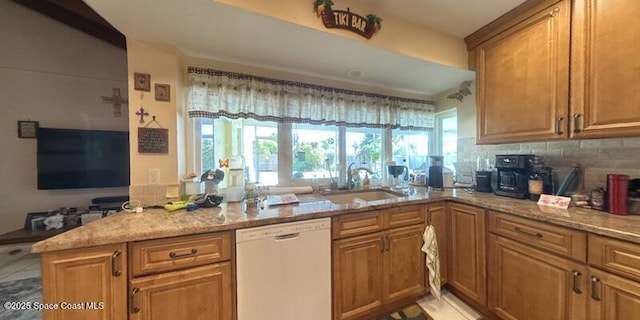 699 Bimini Rd, Satellite Beach, FL 32937 - kitchen with white dishwasher, light stone counters, backsplash, and brown cabinetry